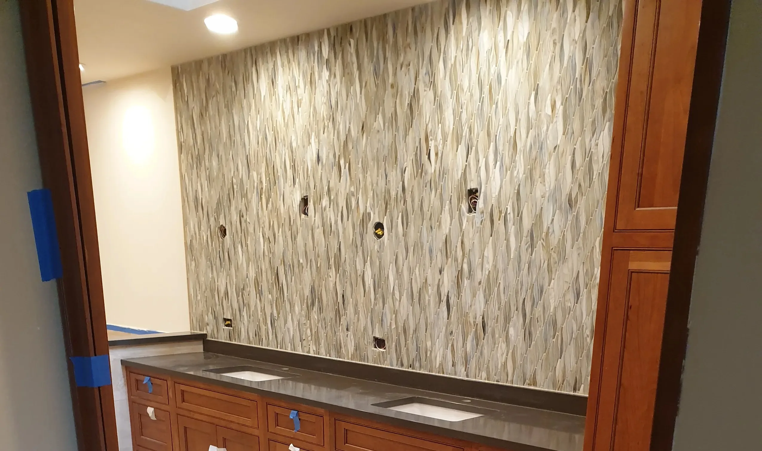 Mosaic tile Backsplash installation on bathroom wall during renovation