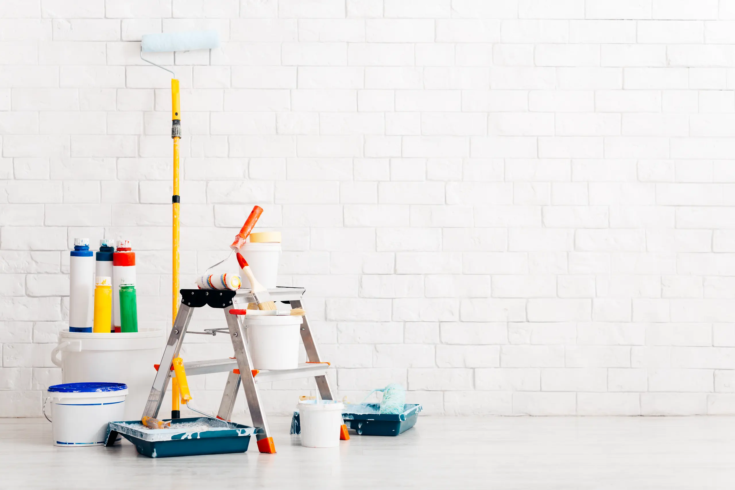 A ladder with painting supplies, including rollers, brushes, and paint cans for interior painting