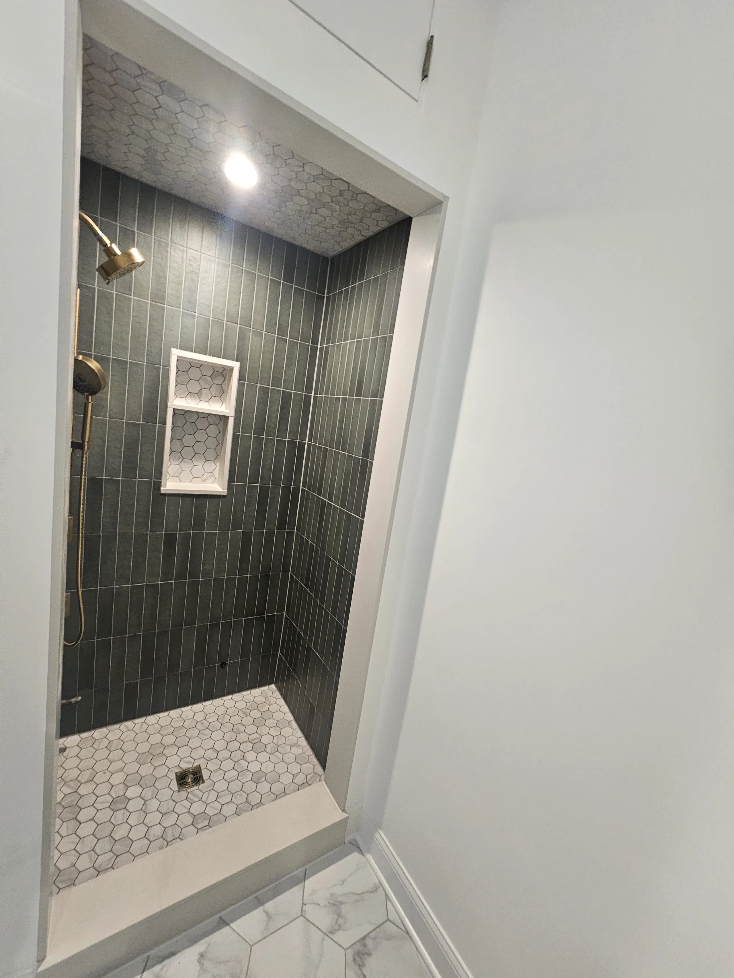 Modern shower remodel featuring hexagon tiles, a built-in niche, and a sleek design