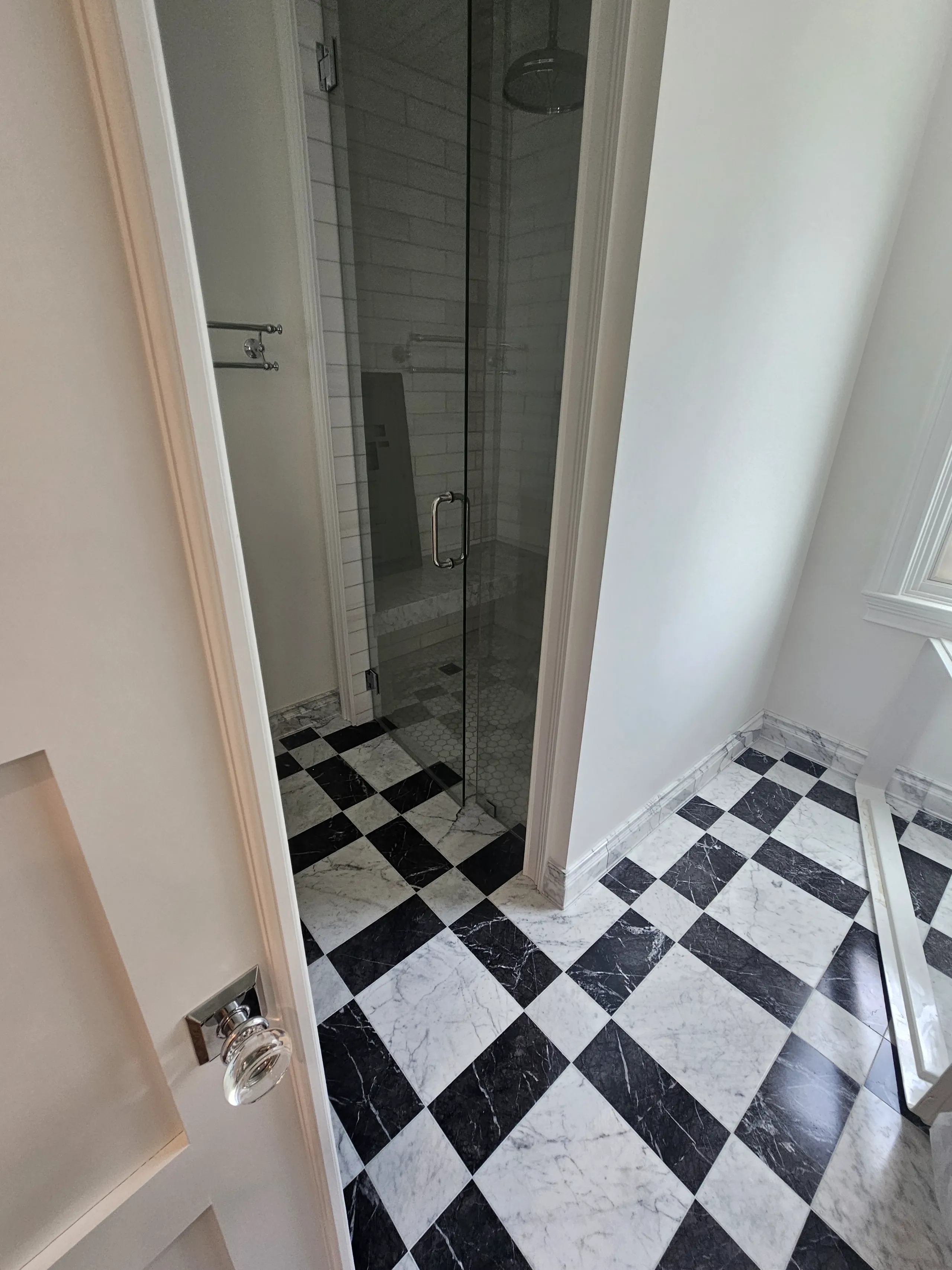 Modern bathroom with a glass shower and black-and-white tile flooring