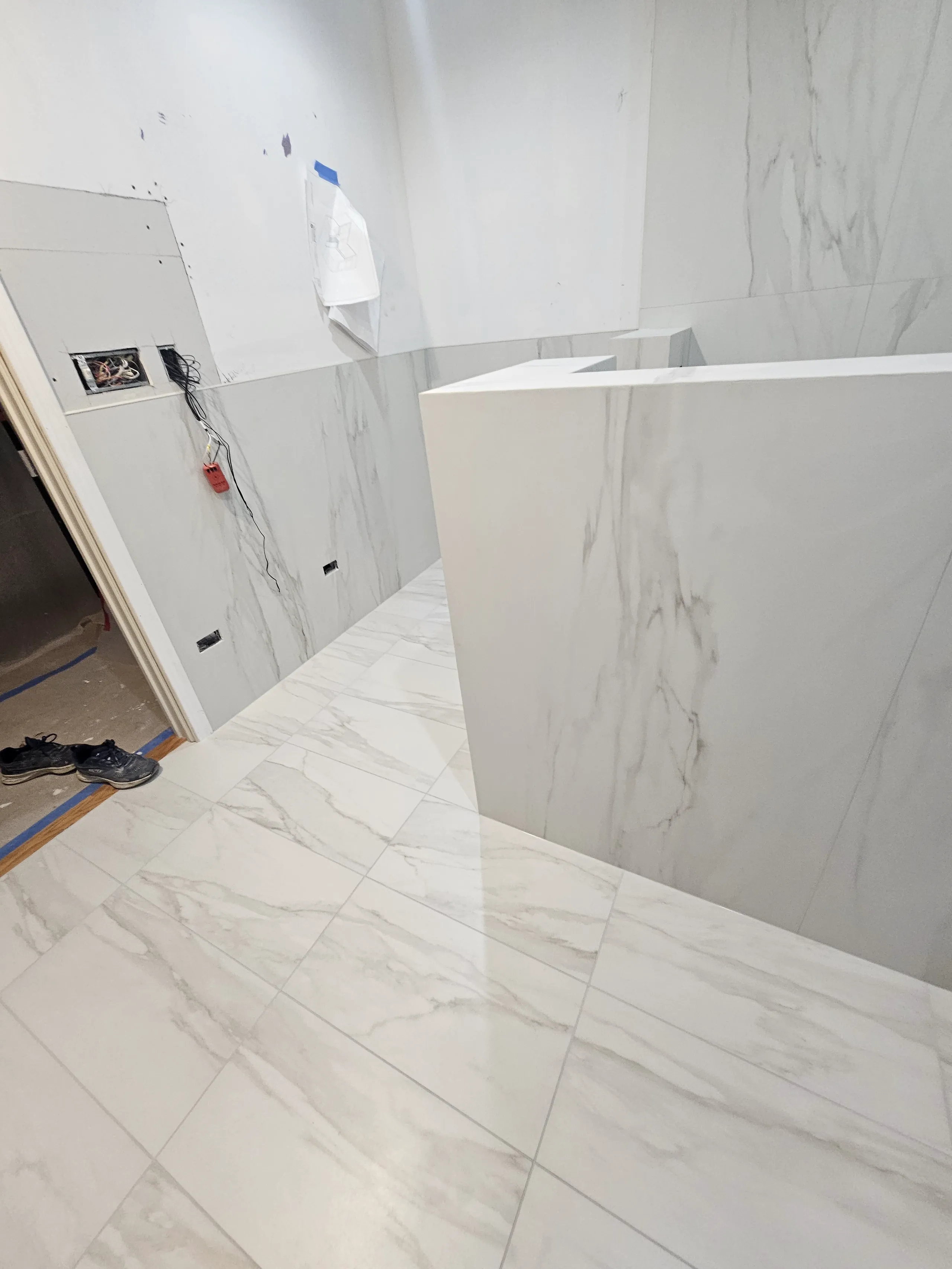 Modern bathroom renovation featuring marble tile flooring and wall panels